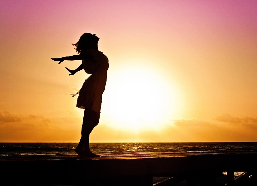 태양이 떠오르는 바닷가에서 사람의 실루엣이 있는 사진