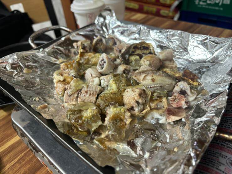 은박지 위에 구워진 곰장어가 있다.
구워진 곰장어의 색깔은 노란색과 갈색이다.