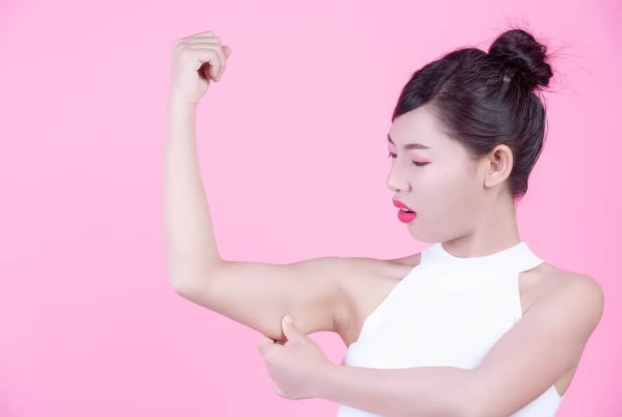 여성이 자신의 팔뚝살을 잡아당기고 있습니다.