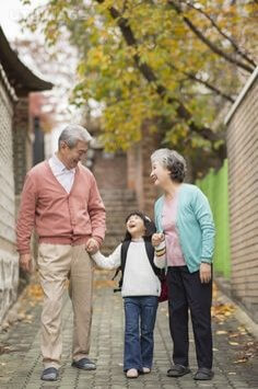 주황색-조끼를-입은-할아버지와-연두색-조끼를-입은-흰머리의-할머니가-손주-손을잡고-골목길을-걸어오는-모습