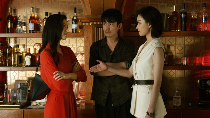 두 여성이 바에서 서로 대면하며 대화하고 남성이 그 사이에서 지켜보는 장면, 영화 사라진 그녀 스틸컷