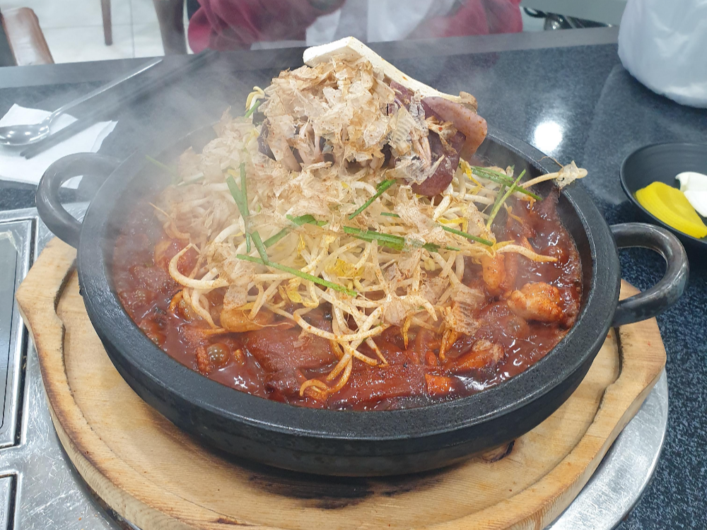 돌짬뽕. 돌판 위에 짬뽕 양념과 면 그 위에 숙주와 오지어 한 마리가 올려져 있다.