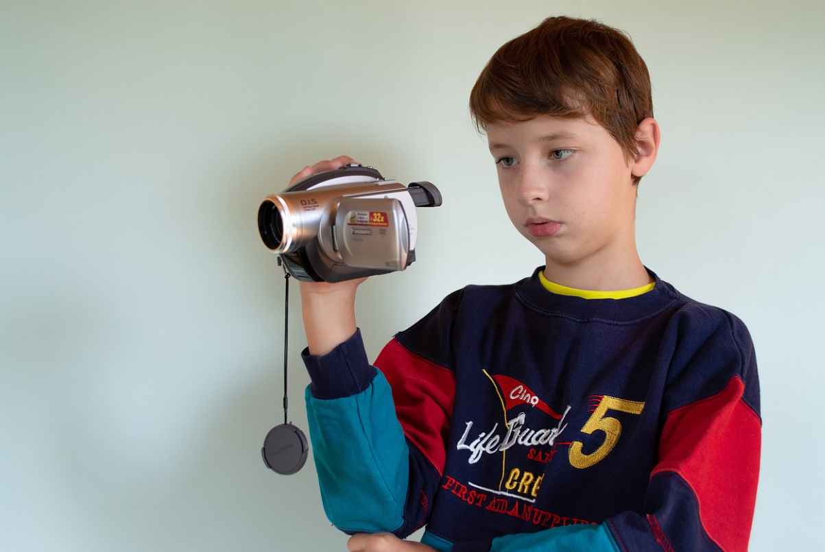 작은 캠코더를 오른손에 들고 촬영에 집중한 남자 아이 사진