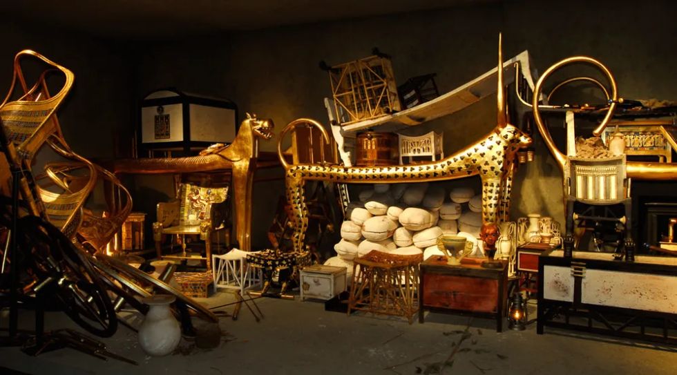 투탕카멘 무덤 안에 어지럽게 쌓여 있는 다양한 부장품. 금으로 된 표범 침대, 의자, 마차, 화장품 상자와 항아리 등이 가득 채워진 모습