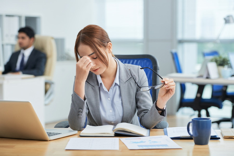 medium-shot-young-asian-woman-sitting-desk-office-rubbing-nose-900