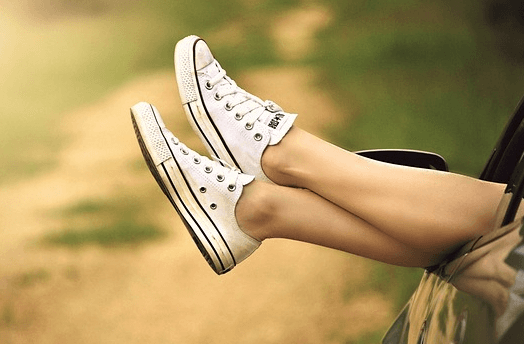 검정 자동차 창밖으로 하얀 스니커즈 운동화를 신은 여자가 두 발을 꺼낸 장면이다.