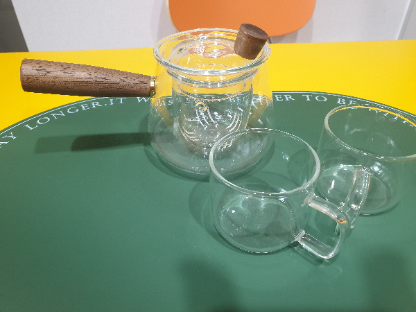 유리로 된 다기 세트 앞쪽에 찻 잔 뒤 쪽에 다관이 보인다. 다관은 우드 손잡이.