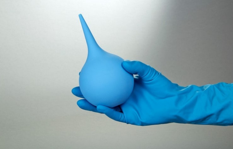 오른쪽 손에 파란색의 고무장갑을 끼고 관장을 할 때 사용하는 파란색 관장기구를 들고 있는 것을 찍은 사진