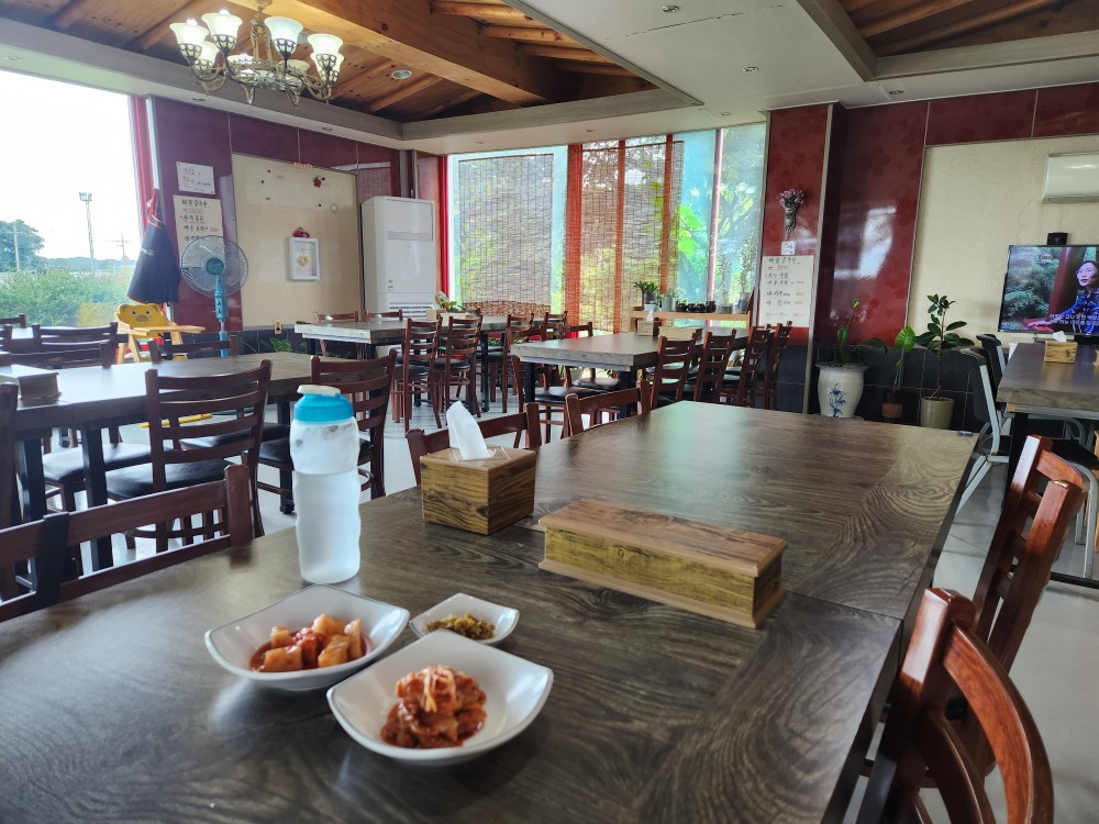 널찍하고 정돈된 식당 내부. 짙은 갈색의 목재 테이블과 의자들이 편안한 분위기를 자아낸다