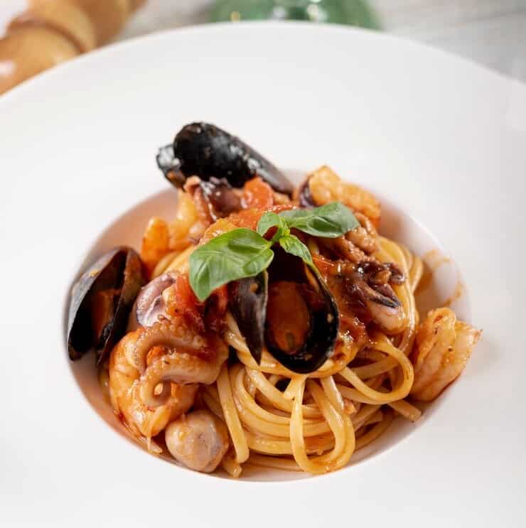 흰 접시에 담긴 홍합, 새우, 오징어 토마토 소스 해물파스타