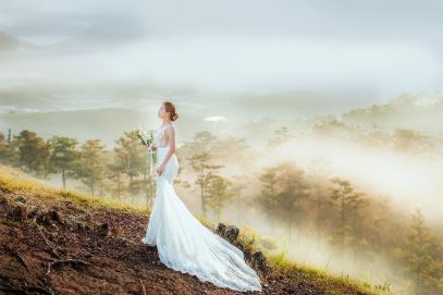 웨딩드레스를 입은 신부가 숲을 배경으로 서있는 사진