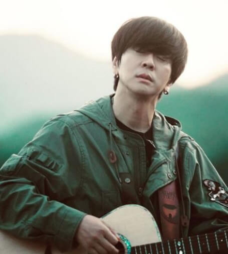윤도현이-야상을-입고-기타를-치며-눈을-감고-음미하고-있는-사진