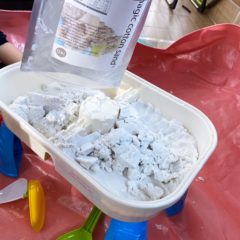 하얀색 놀이용 모래를 테이블 안에 붓고 있다