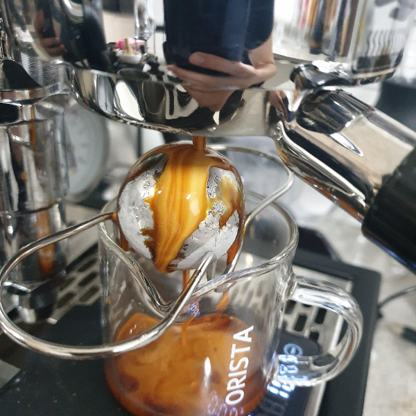 커피 머신에서 커피가 추출되고 있다. 추출된 커피는 칠링볼 위로 떨어지고 있다.