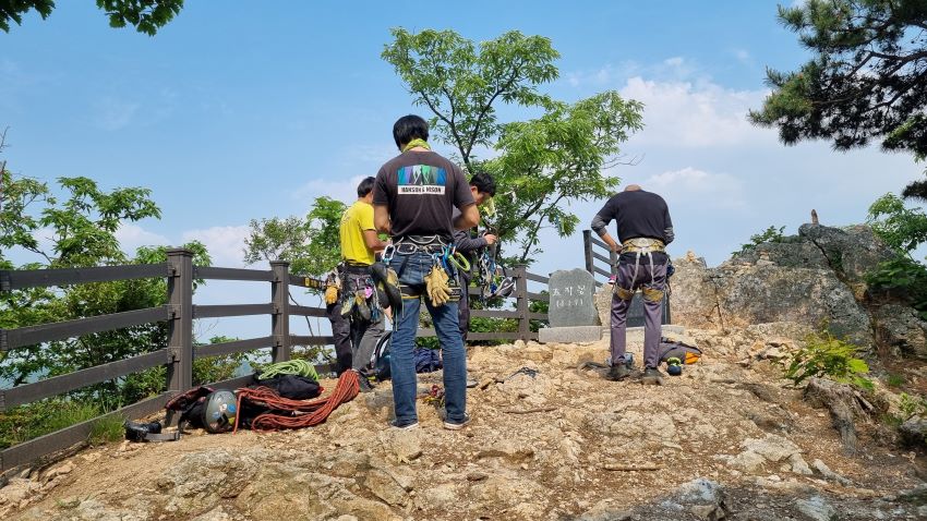 정상 바위 위에 서서 암벽 등반 장비 점검 중인 남 4, 푸른하늘,