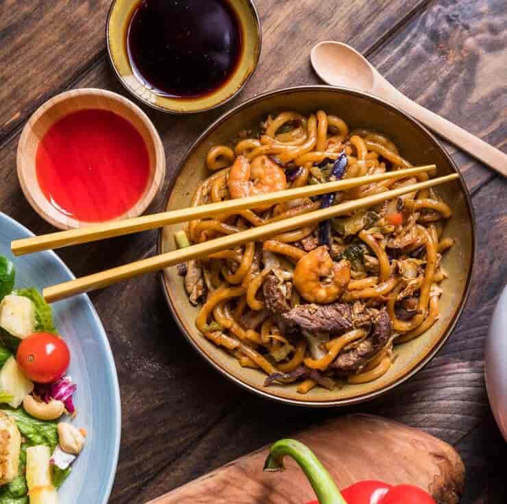 소고기와 새우, 채소가 어우러진 볶음우동 한 그릇 , 간장소스, 칠리소스, 샐러드가 함께 차려진 상차림