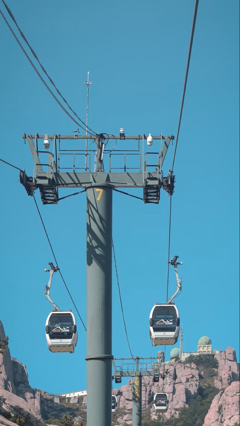 중국 칭다오 라오산에서 운행 중인 케이블카가 파란 하늘 아래 바위산을 가로지르는 모습