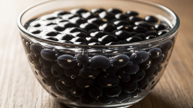 작은 유리 볼에 검은콩을 넣고 찬물을 가득 부어 불리는 모습