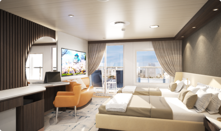 “팬스타미라클호의 로얄 스위트룸 내부 모습. 침대 두 개가 나란히 놓여 있고, 전면에는 바다 전망이 보이는 발코니가 있으며, 밝은 조명과 커튼이 어우러져 고급스럽고 아늑한 분위기를 연출한다. 소파와 TV, 책상, 라운지 체어 등이 갖춰져 있다.”