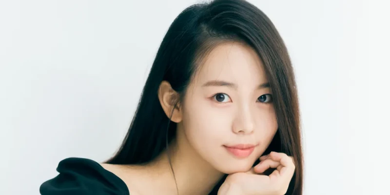 흰색 배경에 검은색 드레스를 입고 턱을 한속에 대고 미소 짓는 배우 정다은