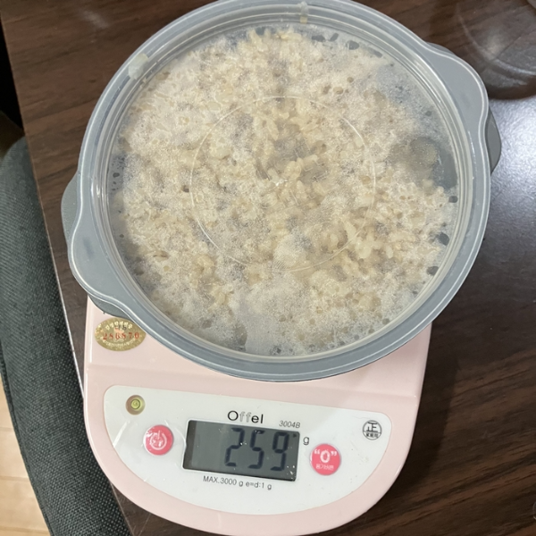 전자저울에 올려진 투명 뚜껑 원형 용기 속 200g 현미밥과 표시된 총 무게 259g