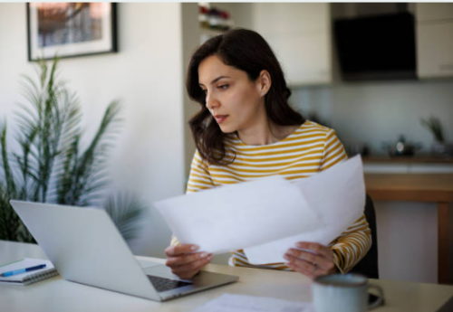 서류확인하며 노트북 화면 보고있는여자이미지