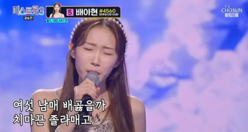 미스트롯3- 보라색 배경의 무대 앞 흰드레스를 입고 오른손으로 마이크를 잡은채 노해하는 정서주