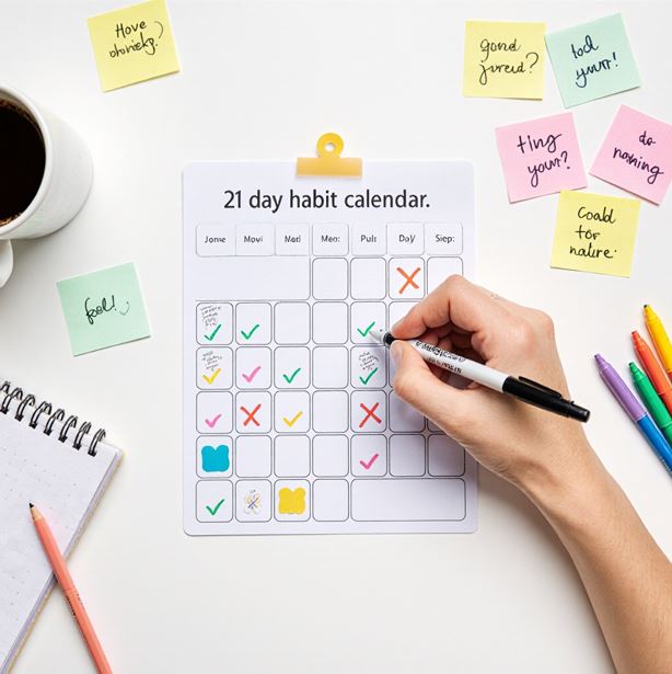 21일 습관을 만들기 위해 달력에 체크 표시하는 손의 모습