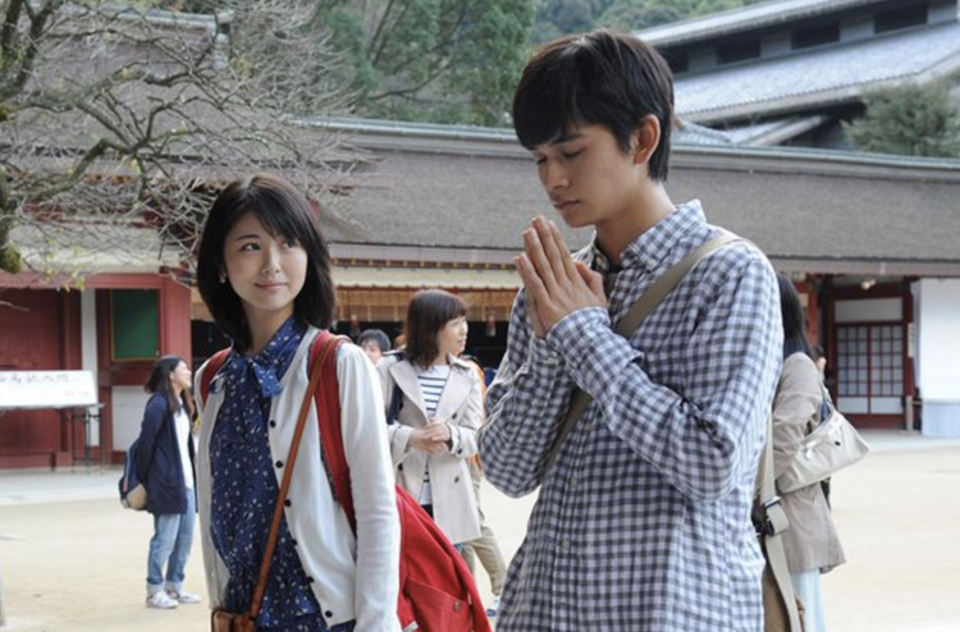야마우치 사쿠라와 시가 하루키가 신사 앞에서 마주 선 장면, 소원을 비는 하루키를 따뜻한 미소로 바라보는 사쿠라