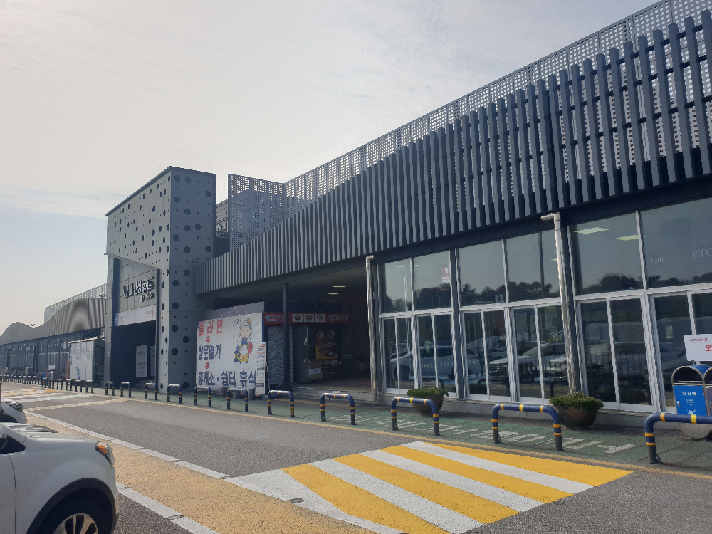 옆으로 넓은 회색 건물. 철제 프레임과 유리가 깔끔하다