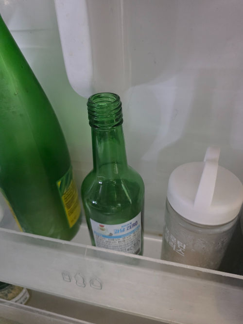 냉장고 문 안쪽에 보관 중인 먹다 남은 소주병과 살림 재료 사진