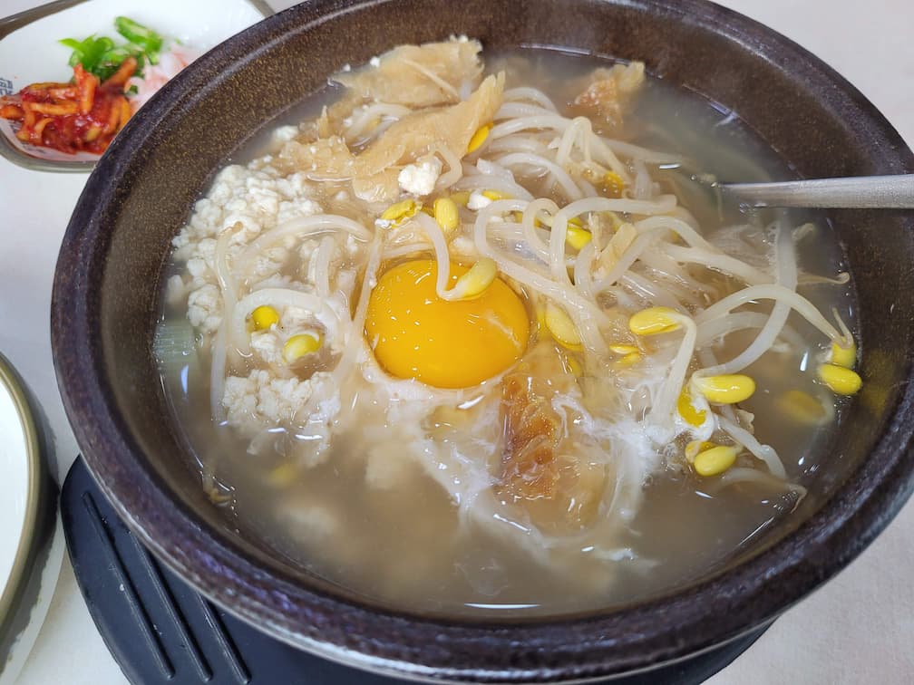 뚝배기에 담긴 황태콩나물국밥과 콩나물, 황태, 순두부 구성