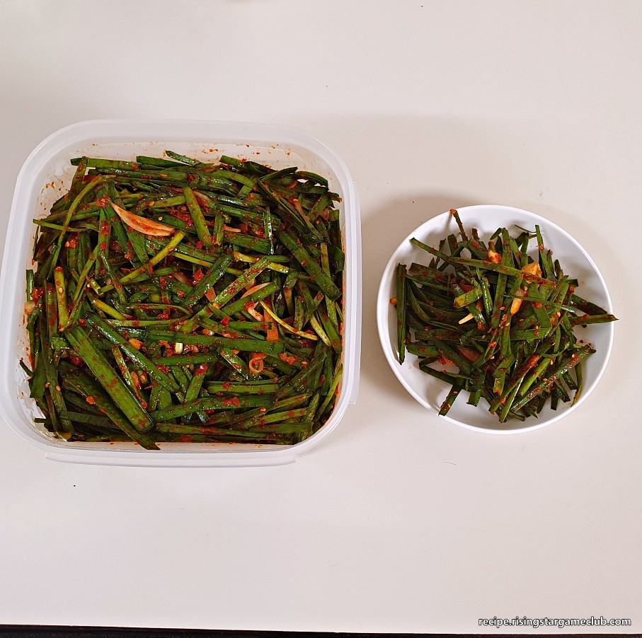 완성된 부추 겉절이를 밀폐 용기와 접시에 담아 놓은 사진