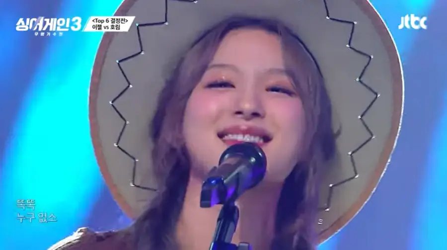 싱어게인3-
카우보이 모자를 쓰고 양갈래 머리를 딴채 스탠딩 마이크 앞에서 웃으며 노래하는 66호