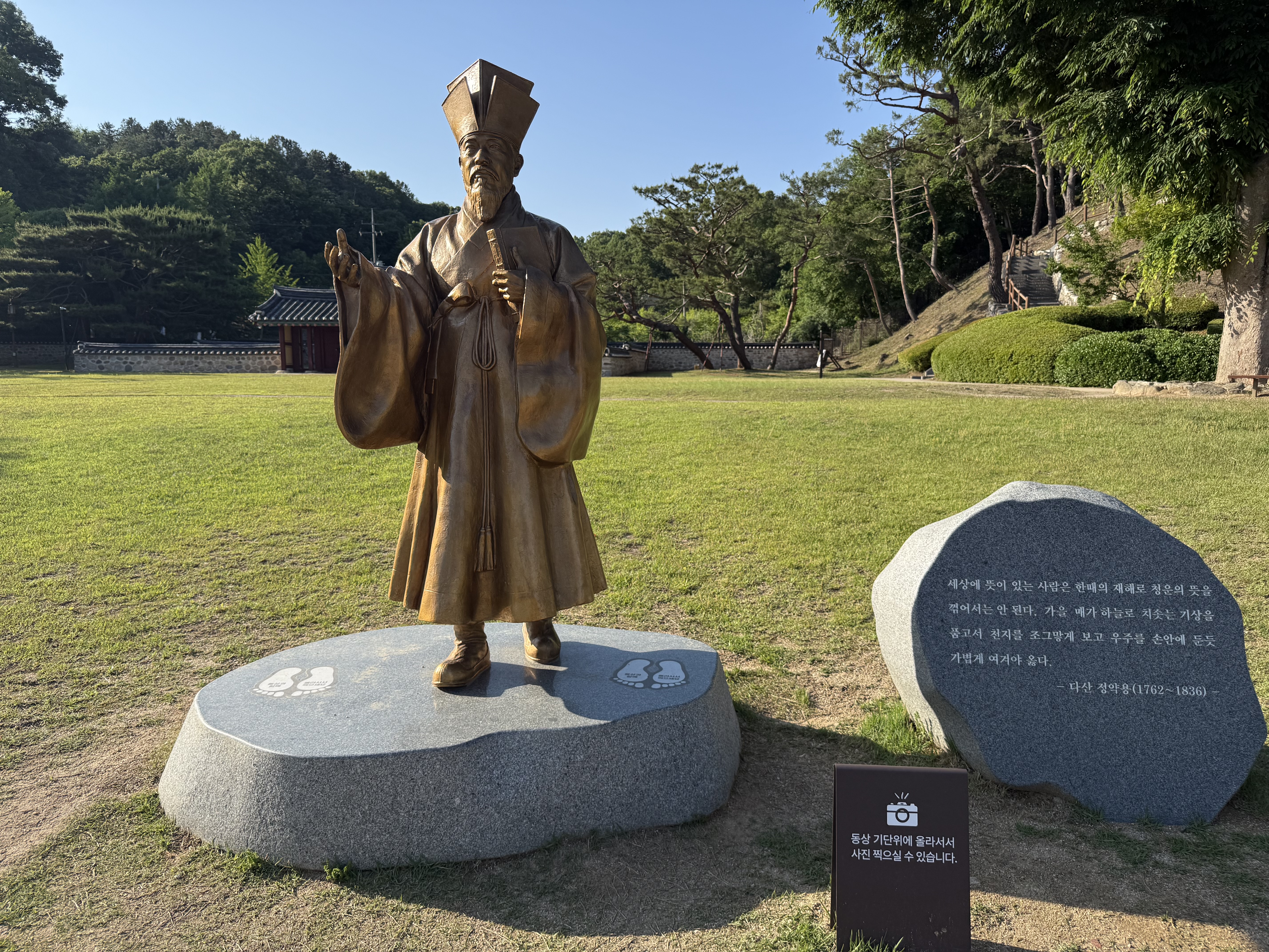 정약용 선생의 동상. 푸른 잔디밭 위에 서 있으며, 동상 옆에는 선생의 명언이 새겨진 비석이 있다.