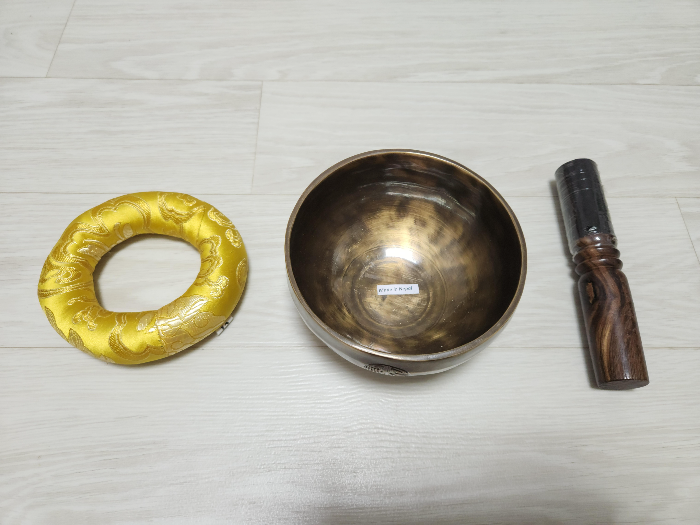 The resting bell stand, bowl, and stick are placed on the floor.