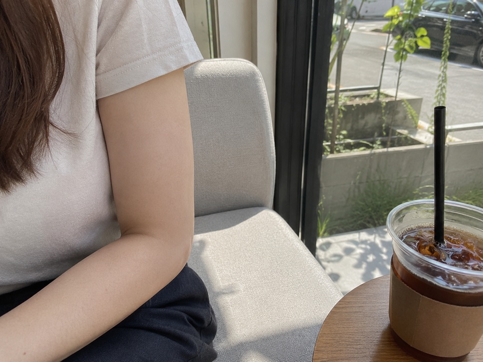 햇빛 들어오는 카페 창가에서 반팔을 입고 편안하게 앉아 있는 자연스러운 일상 모습