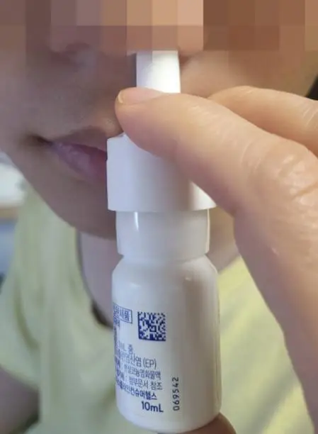 코에 오트리빈 노즐을 넣고 손가락으로 펌프를 누르며 분사하고 있는 이미지