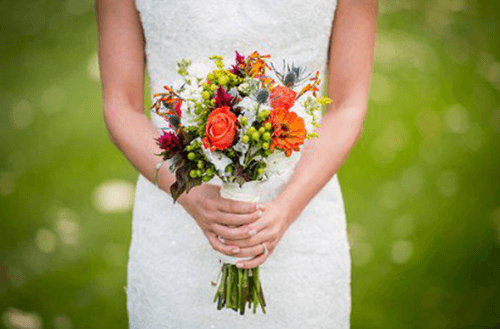 한 여인이 분홍색 빨간색 흰색 꽃다발을 들고 있는 모습