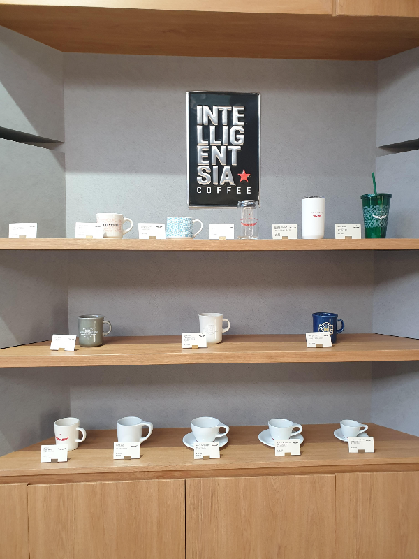 머그컵과 유리잔 및 텀블러 등의 굿즈가 전시되어 있다.