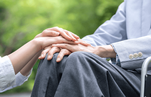 요양병원 환자와 보호자의 손을 맞잡은 모습 &ndash; 본인부담상한제 직접 신청 대상 안내