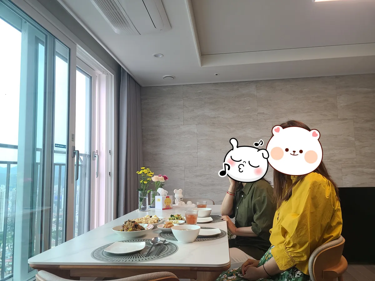 베란다-창밖이보이는-화이트대리석테이블-2명의여자친구들이-웃으며-식탁의-음식들을-바라보고있음