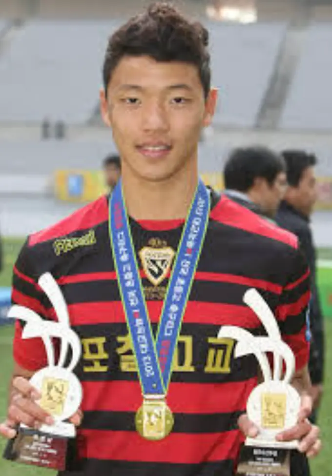 붉은색과 검은색 스트라이프 가슴가운데 황금색 글씨 포철고교 유니폼을 입고 파란줄 메달을 목에 걸고 있는 황희찬