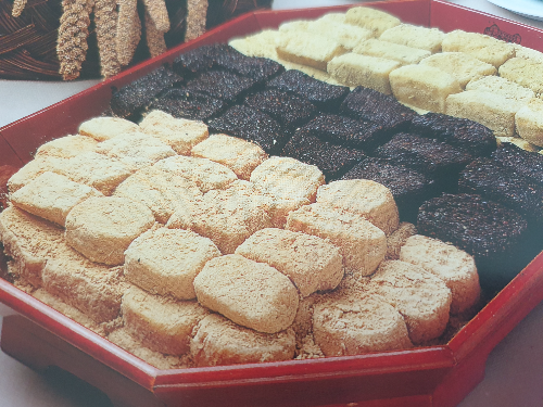 콩가루와 흑임자가루로 고물을 해서 만든 인절미가 목기 그릇에 담겨있는 모습