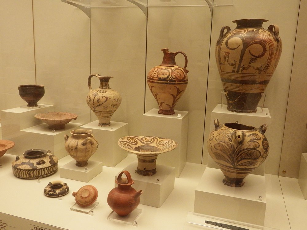 박물관 진열장에 전시된 미케네 유적의 도자기 유물들. 다양한 크기와 형태, 그리고 독특한 문양이 그려진 항아리와 그릇들이 정렬되어 있다.