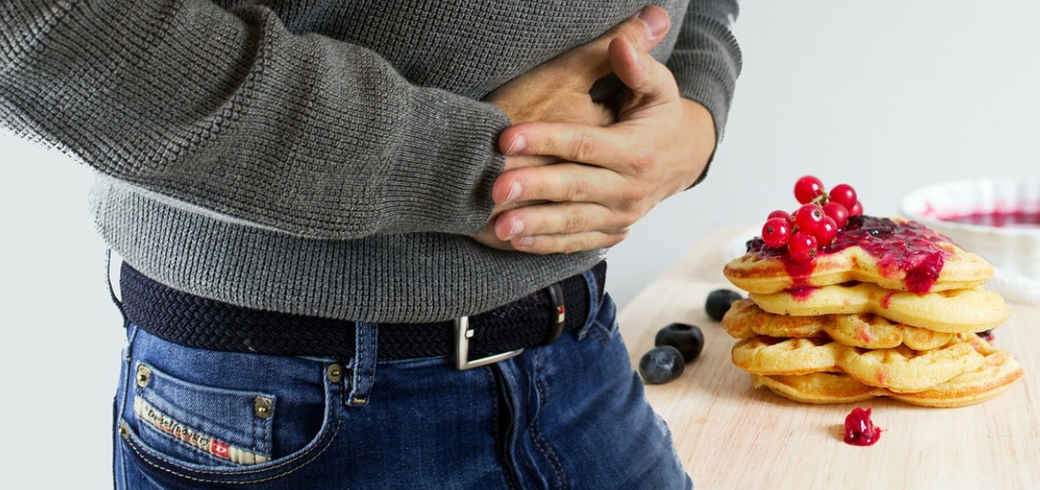 과식을 해서 소화가 안되서 두 손으로 배를 잡고 있는 남성