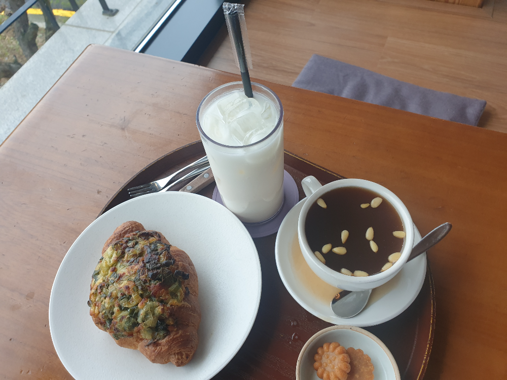 우드 테이블 위에 가을밤 라테, 계피 생강차, 대파 크로아상이 놓여있다.