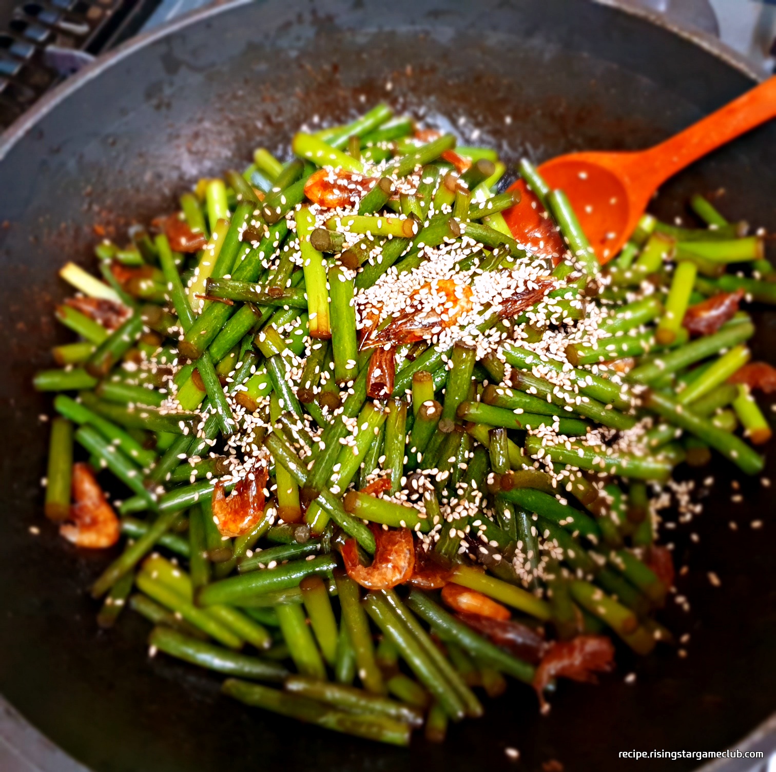 완성된 마늘종 새우 볶음에 깨를 뿌리는 사진