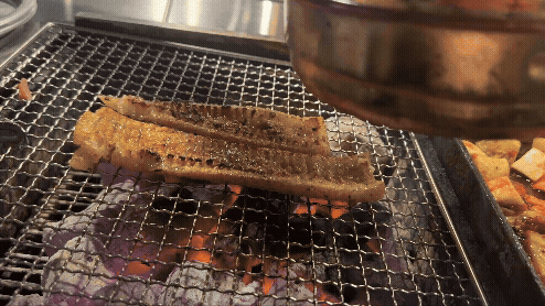 직원이 뜨거운 판으로 돼지껍데기를 눌러 지져 바삭하게 만드는 장면의 GIF