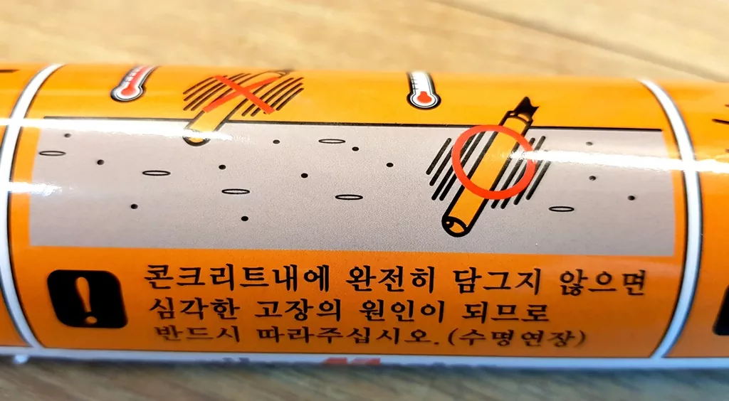 진동봉 헤드의 "콘크리트 내에 완전히 담그지 않으면 심각한 고장의 원인이 되므로 반드시 따라주십시오" 경고 문구.